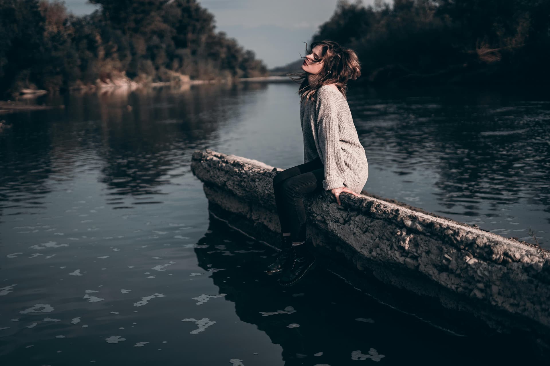 Vrouw in meditatie aan een rustige rivier in de natuur